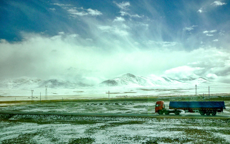 Tibet, China - Oct 2010: Haulage trucks drive across the Tibetan Plateua, as seen from the High Altitude Qinghai - Tibet railway between Beijing and Lhasa, the worlds highestのeditorial素材