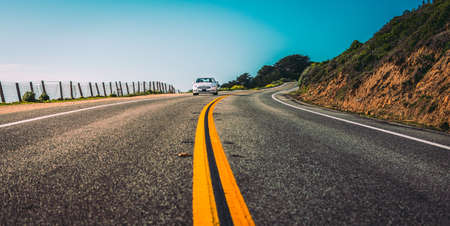 Modern white sedan car on US highway, distant frontal view, highway 1 california, summerの写真素材