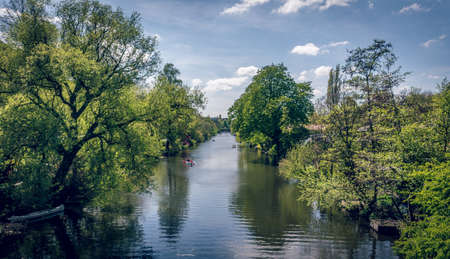 river landscape with green trees alongside, boats and reflections in water during summerの写真素材