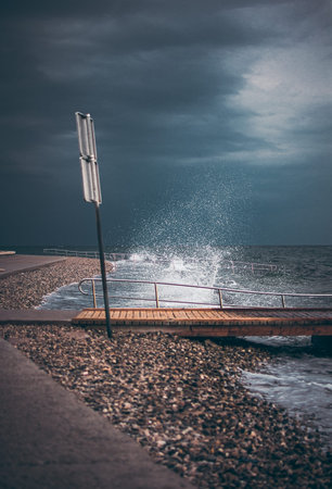 Breaking waves on promenade with warning sign