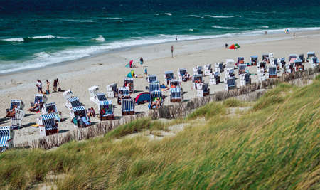 Kampen, Germany - August 6, 2017: Crowded Beach with strandkorbs, beach basket chairs, and dunes during summer vacation and afternoon light near Kampen on Sylt at the North Sea, Schleswig-Holstein, Germany.のeditorial素材