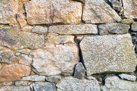 Stone wall texture made from uneven sized rocks with twigs and cobwebs in the gapsの写真素材