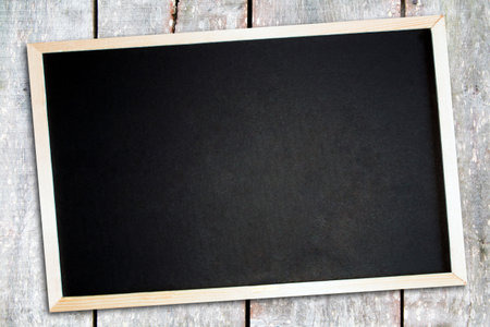 Blackboard in a wooden frame blank to add your own message laying on a weathered wood background