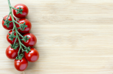 Vine ripened cherry tomatoes on a wooden board from an overhead perspective with copy spaceの写真素材