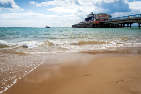 Bournemouth, Dorset, UK - August 29, 2006: Bournemouth sandy beach and pier with waves splashing in on a cloudy summer dayのeditorial素材