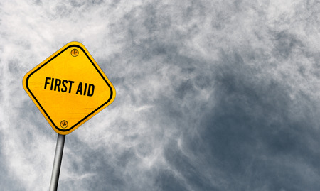 first aid - yellow sign with cloudy skyの写真素材