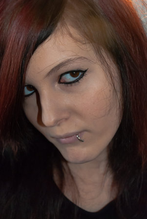 Young punk emo girl with piercing, with red and black hair, looking at camera with serious facial expression, close-upの写真素材