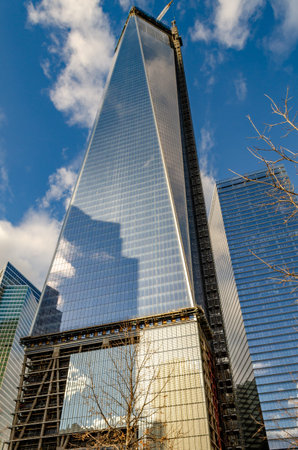 One World Trade Center construction area with clouds reflection in the window, crane on top during...
