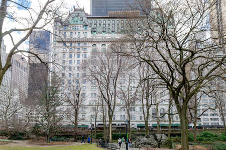 The Plaza Hotel, New York City during winter with trees and tree branches in forefront, people walking in Central Park, focus on background, horizontalのeditorial素材
