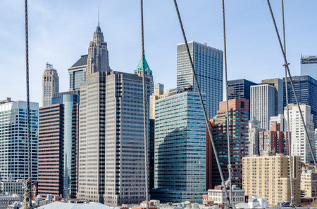 Skyline of Manhattan during daytime with clear sky with wire ropes of Brooklyn Bridge in the...