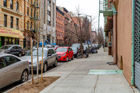 Street in Harlem with retail store and different old residential building facades, cars parked at the street, during winter day with overcast, horizontalのeditorial素材