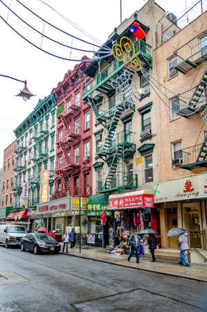 Retail Stores at China Town, New York City, People walking with umbrellas in the front of the stores, during rainy winter day with overcast, decoration above the street, verticalのeditorial素材