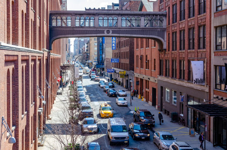 City street in Chelsea with yellow taxi cab and van passing by, aerial view from the High Line...