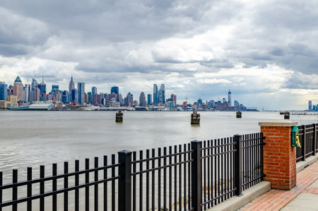 View of Manhattan Skyscraper from the Other side of Hudson River with fence in front, New Jersey during cloudy winter day, wide angle shot horizontallyのeditorial素材