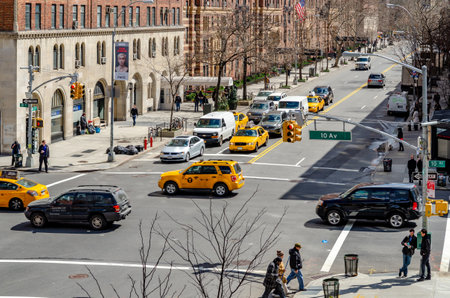 Crossroads at Chelsea, New York City with lots of yellow taxi cabs and cars passing by during sunny winter day, brown building facades in the background, horizontalのeditorial素材