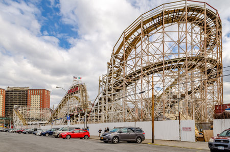 Cyclone Wooden Rollercoaster at Luna Park Amusement Park, Coney island, view from the side, Brooklyn, New York City during winter day with cloudy sky, cars parked in front, horizontalのeditorial素材