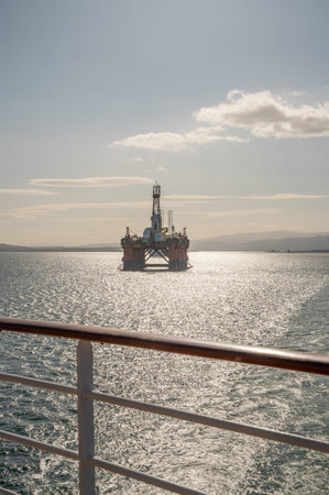 Transocean Leader oil platform at Invergordon during sunset, cruise ship railing in front, vertical...