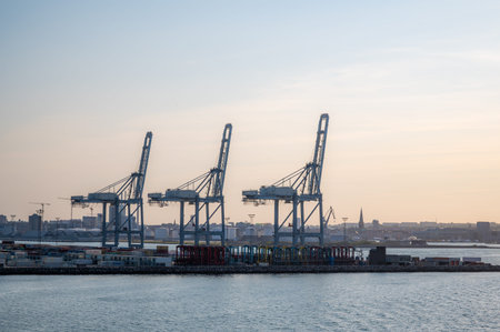 Blue freight cranes at the Port of Aarhus, Denmark during sunset, side view from the distance