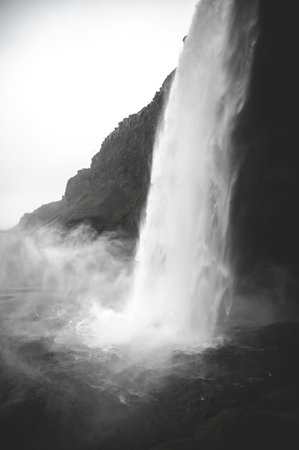 Seljalandsfoss Waterfall side view black and white during rainy weather, Iceland, vertical shotの写真素材