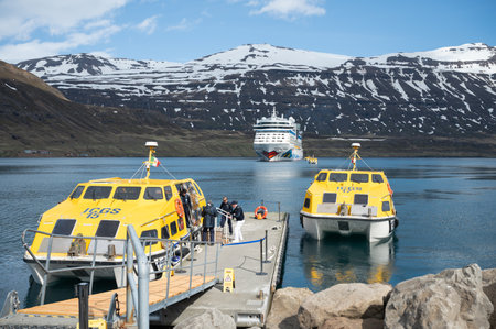 AIDA Bella at the Fjord of Seydisfjordur with two yellow lifeboats in front and snow mountain in the background, wide angle shot, Icelandの写真素材