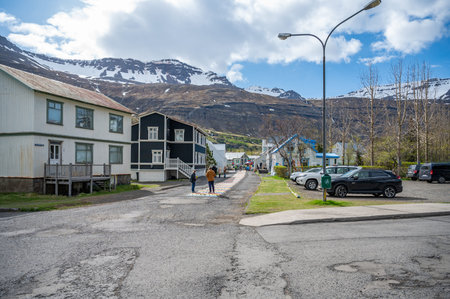 City center of Seydisfjordur with rainbow walking path on the street, view from the wooden church, residential buildings, mountain range in the background, Icelandの写真素材