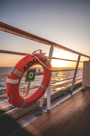 Orange AIDA Bella lifebuoy attached to ship railing, sunset with sea and sunlight in the background, vertical shotのeditorial素材