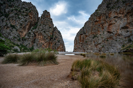 Sa Calobra, Mallorca beach between rocky mountain walls during cloudy weather, lake and plants in front, wide angle shot, Majorcaの写真素材