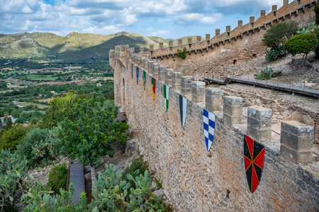 Castell de Capdepera, Mallorca castle wall with flags coat of arms on the wall, mountain landscape in the background, Majorcaの写真素材