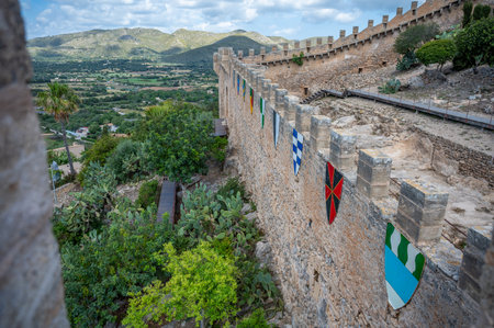 Castell de Capdepera, Mallorca castle wall with flags coat of arms on the wall, mountain landscape in the background, Majorcaの写真素材