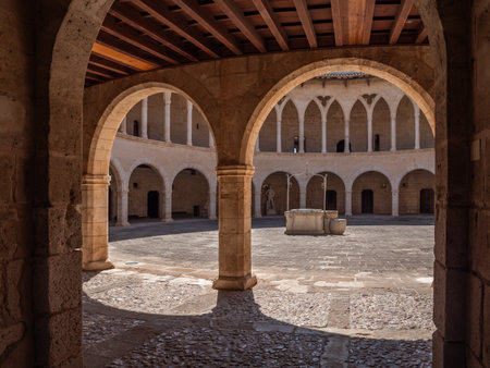 Bellver Castle. Palma de Mallorca, historic courtyard features a circular design with stone arches and a central fountain, bathed in sunlight, Majorcaの写真素材