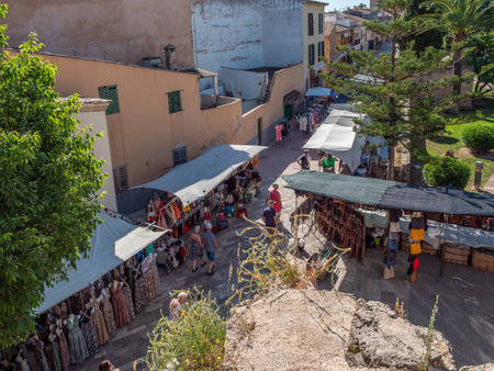 Alcudia market, Mallorca, bustling street in a quaint town lined with shops and outdoor cafes, with people strolling and enjoying the sunny day, Majorcaの写真素材