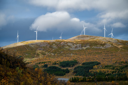 Sortland, scenic landscape featuring wind turbines on a hill with autumn foliage, set against a partly cloudy sky, Norwayの写真素材
