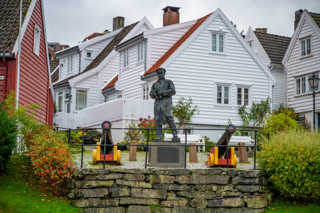 A man stands in front of a row of white houses with red roofs, surrounded by cannons and a stone wallの写真素材