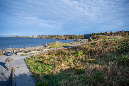 Kyststien, Haugesund, Norway, scenic coastal area with a road, parked cars, and people enjoying the...