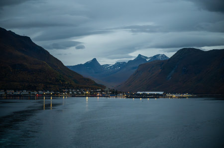 Narvik, Norway serene harbor town nestled between towering mountains, with a calm body of water reflecting the twilight skyの写真素材