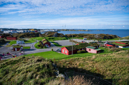 Haugesund, Norway coastal village with red buildings, green roofs, and a scenic view of the sea and...