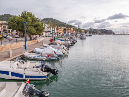 Andratx, Mallorca, serene marina with various boats docked along a waterfront lined with colorful buildings, under a cloudy sky, Majorcaの写真素材