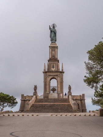 Estatua Cristo Rei de Sant Salvador, Mallorca, grand monument featuring a statue of a figure holding a cross, set on a tall pedestal with stairs leading up to it, surrounded by statues and situated in a park-like setting, Majorcaの写真素材