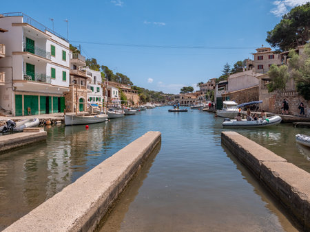 Cala Figuera, Mallorca, harbor scene with boats docked along the water, surrounded by charming Mediterranean-style buildings under a clear blue skyの写真素材