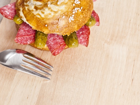 german bread roll with salami slices on a wooden plateの写真素材