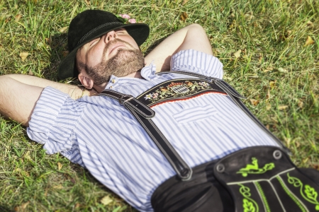An image of a traditional bavarian man relaxing in the grassの写真素材