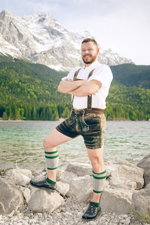 A traditional bavarian man at lake Eibsee with the Zugspitze mountain in the backgroundの写真素材