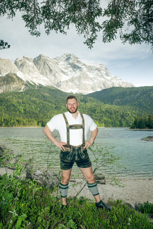 A traditional bavarian man at lake Eibsee with the Zugspitze mountain in the backgroundの写真素材