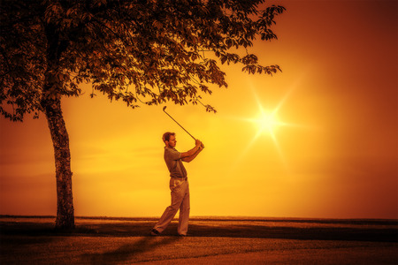 An image of a young male golf player at sunsetの写真素材