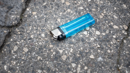 An image of a lost blue cigarette lighter at the asphaltの写真素材