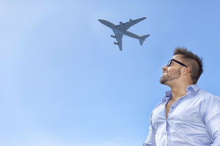 A bearded man in front of a blue sky with an airplaneの写真素材