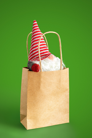 A christmas gnome in a paper bag isolated on greenの写真素材