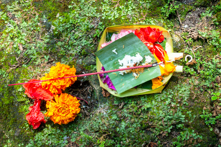 Votive offering with colorful flowers, cookies, greenery and ribbons arranged on a green leaf place on old weathered stonesの写真素材