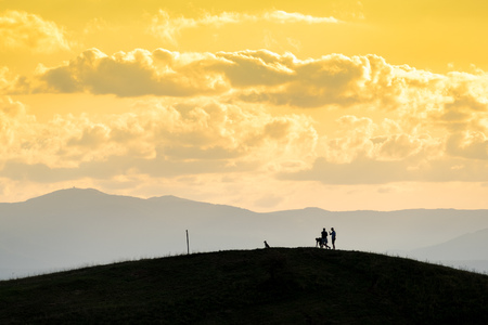 An image of a couple and the dog out for a walk at the sunsetの写真素材