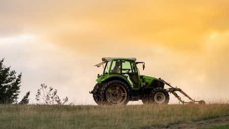An image of a typical tractor in the evening skyの写真素材